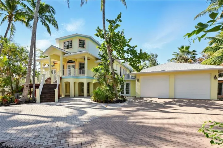 View of front of home featuring a ceiling fan, stairs, stucco siding, decorative driveway, and french doors
