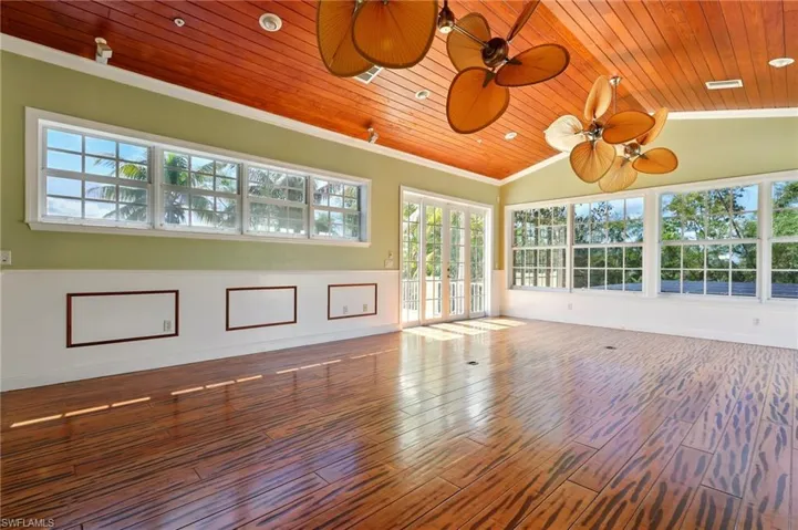 Empty room with plenty of natural light, wooden ceiling, wood finished floors, crown molding, and baseboards