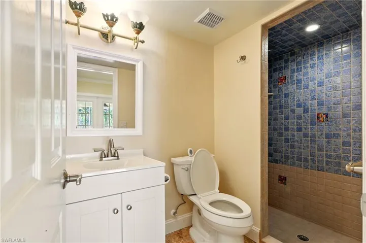 Full bathroom featuring a tile shower, toilet, vanity, and baseboards