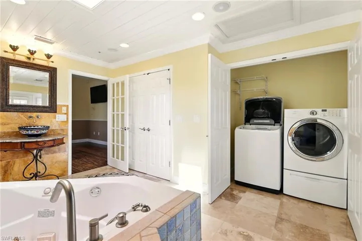 Clothes washing area with washing machine and dryer, ornamental molding, baseboards, and recessed lighting