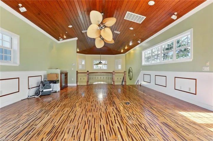 Unfurnished living room with a ceiling fan, wooden ceiling, crown molding, wood finished floors, and plenty of natural light