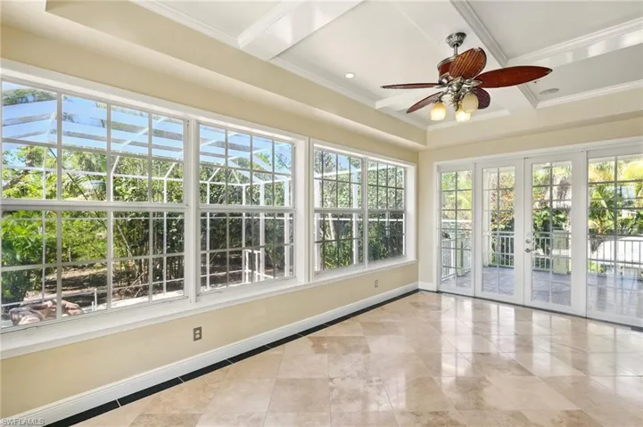 Unfurnished sunroom featuring french doors, healthy amount of natural light, tile patterned floors, ornamental molding, and baseboards
