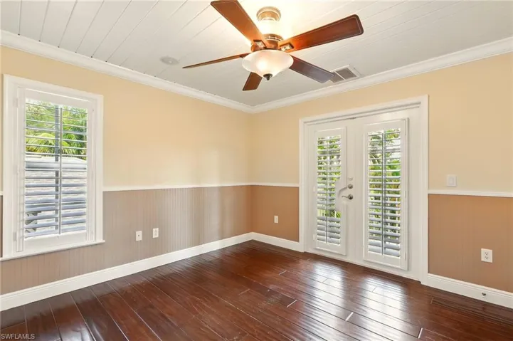 Unfurnished room featuring hardwood / wood-style flooring, wainscoting, baseboards, ceiling fan, and wooden walls