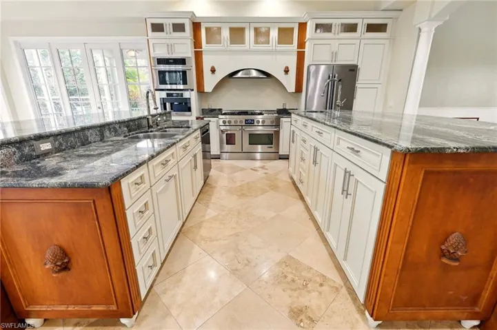 Kitchen with stainless steel appliances, a large island, a sink, and dark stone counters