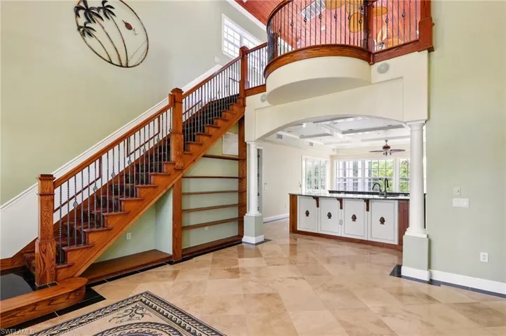 Stairs featuring a towering ceiling, ornate columns, arched walkways, a ceiling fan, and baseboards