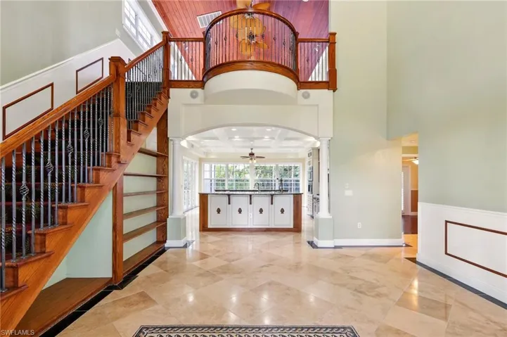 Foyer featuring ornate columns, a high ceiling, arched walkways, ceiling fan, and baseboards