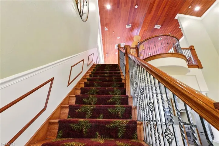 Staircase with wooden ceiling, a decorative wall, a wainscoted wall, recessed lighting, and crown molding