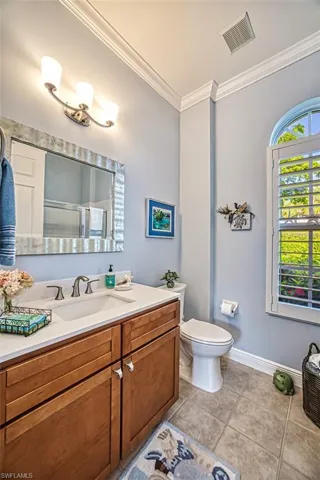 Bathroom featuring vanity, crown molding, tile patterned flooring, and toilet