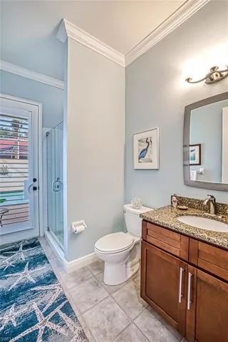 Bathroom featuring vanity, tile patterned floors, walk in shower, crown molding, and toilet