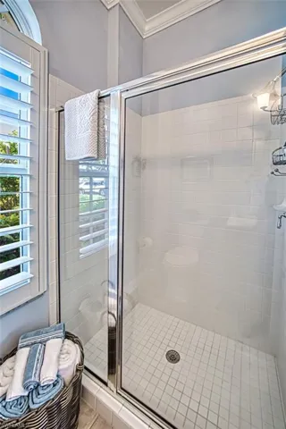 Bathroom with a wealth of natural light, crown molding, an enclosed shower, and tile patterned flooring