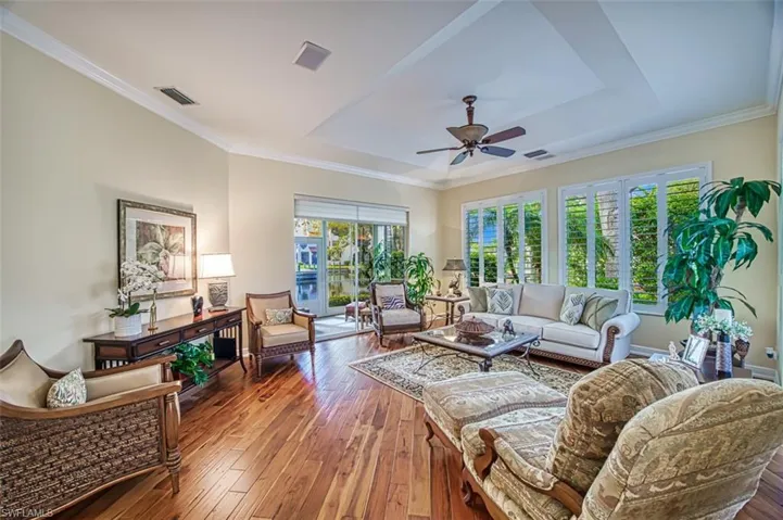Living room with a tray ceiling, ornamental molding, ceiling fan, and hardwood / wood-style floors