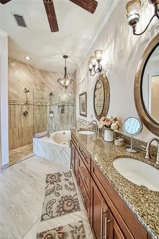 Bathroom featuring tile patterned flooring, double sink vanity, ceiling fan, plus walk in shower, and ornamental molding