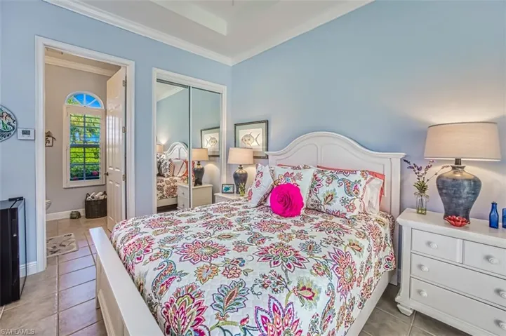 Tiled bedroom featuring crown molding and a closet