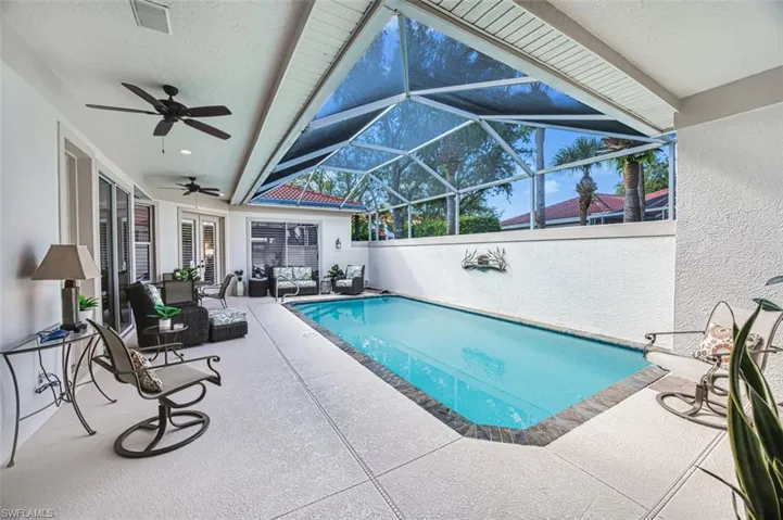 View of pool with a lanai, a patio area, an outdoor living space, and ceiling fan