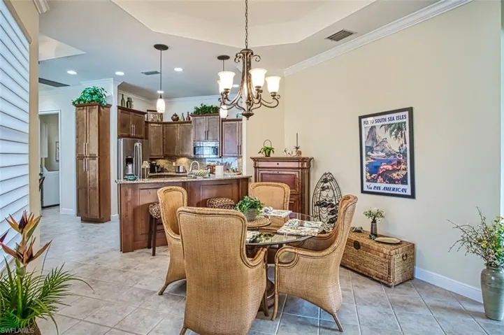 Tiled dining space featuring a chandelier, a tray ceiling, and ornamental molding