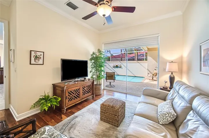 Living room with wood-type flooring, crown molding, and ceiling fan
