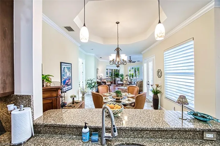 Kitchen featuring crown molding, a chandelier, a tray ceiling, and stone countertops