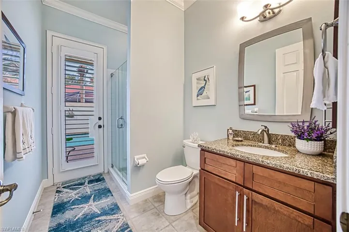 Bathroom featuring vanity, tile patterned floors, crown molding, toilet, and a shower with door