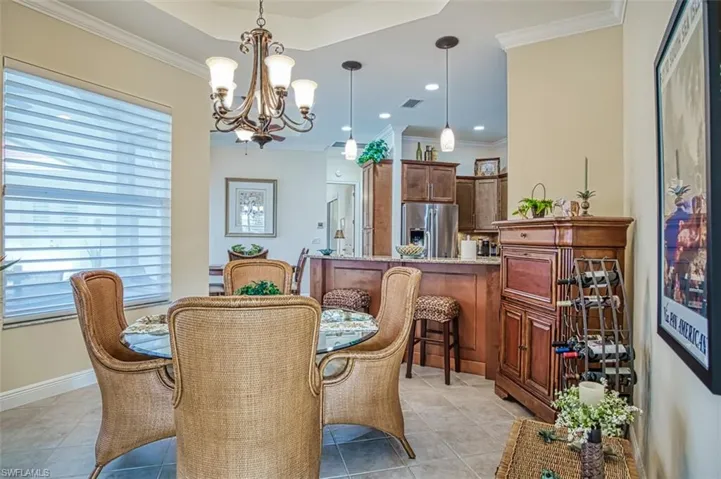 Dining space with light tile patterned flooring, crown molding, and an inviting chandelier