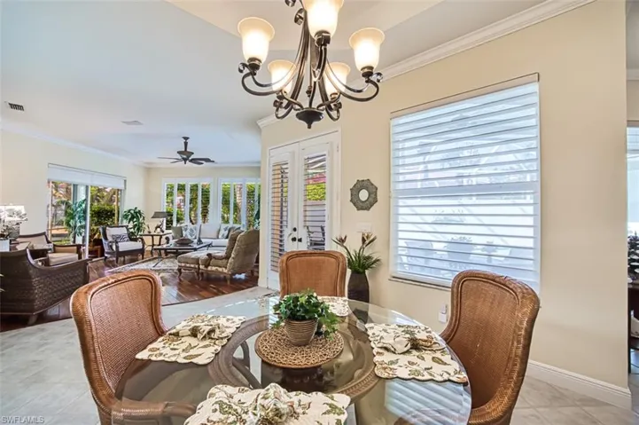 Dining room featuring light tile patterned flooring, ceiling fan with notable chandelier, crown molding, and french doors