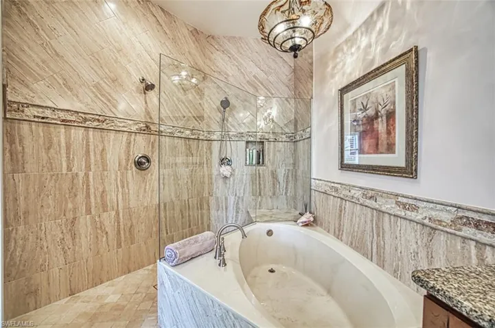 Bathroom featuring vanity, plus walk in shower, and tile walls