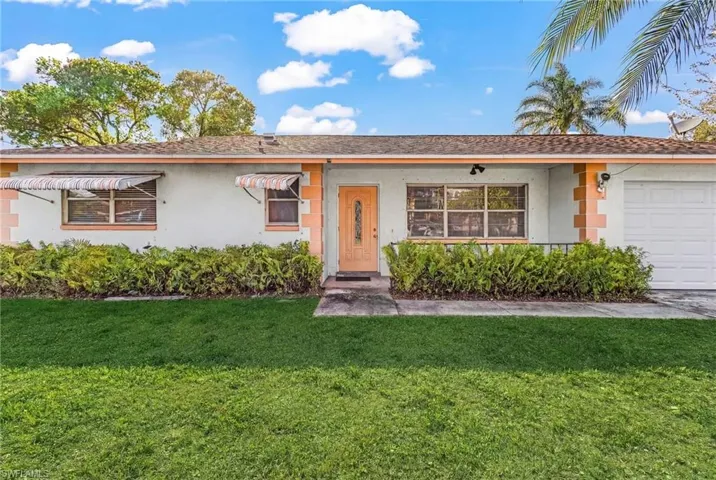 Ranch-style home with a garage, a front yard, stucco siding, and a shingled roof
