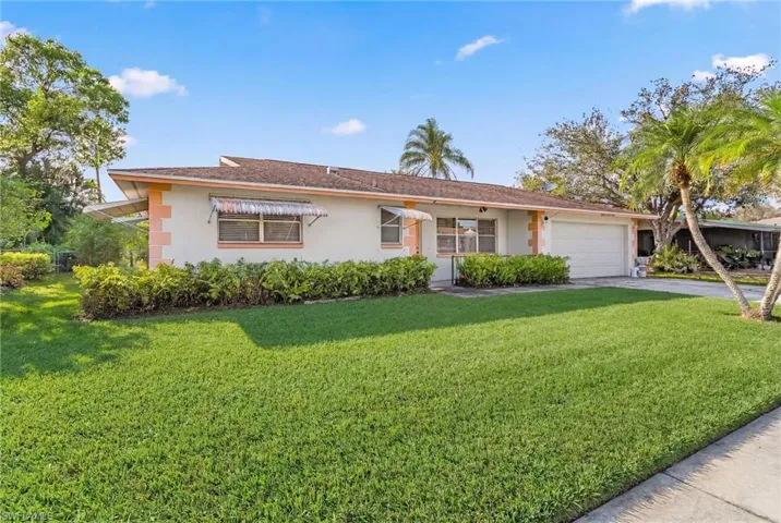 Single story home featuring a garage, a front lawn, stucco siding, and driveway