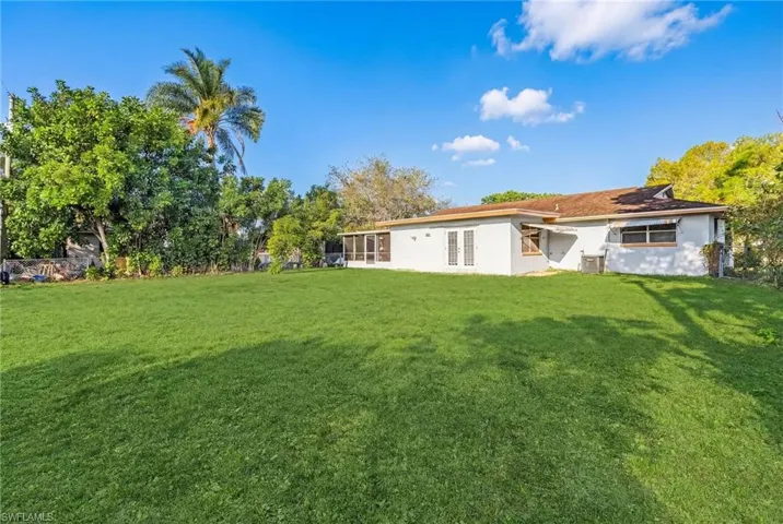 Back of house featuring a lawn, stucco siding, and a sunroom