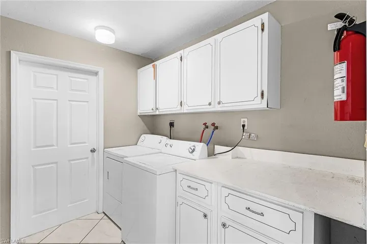 Laundry room featuring cabinet space, separate washer and dryer, and a textured wall