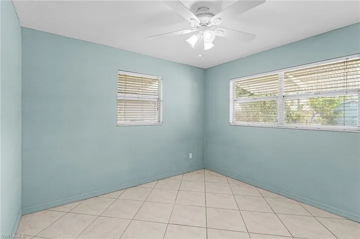 Unfurnished room featuring a ceiling fan, plenty of natural light, and light tile patterned flooring