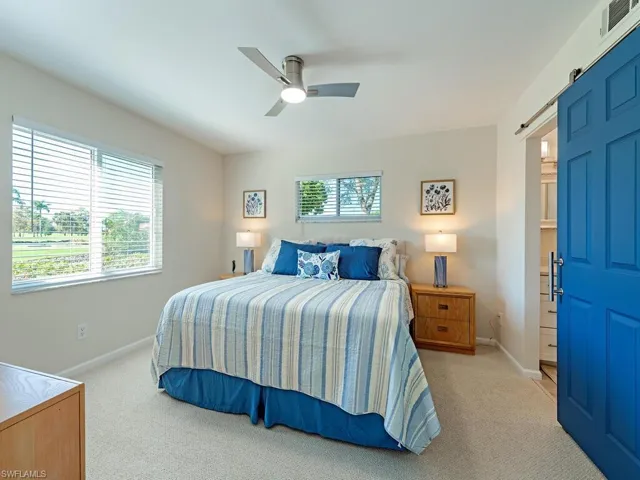 Bedroom featuring a barn door, light colored carpet, and ceiling fan