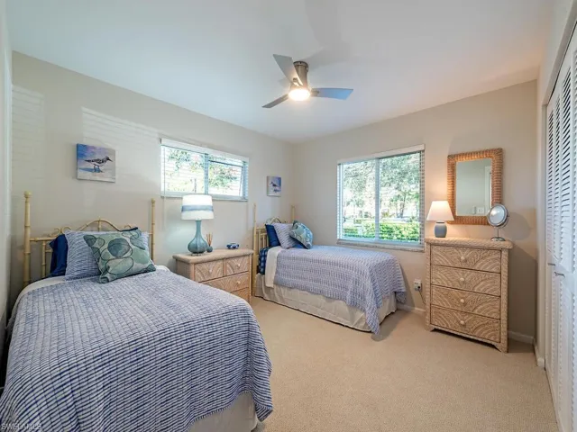 Bedroom with light carpet, multiple windows, and ceiling fan