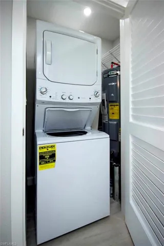 Laundry area featuring stacked washing machine and dryer and electric water heater