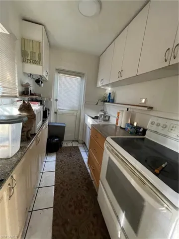 Unit 2: Kitchen with range, light tile patterned floors, white cabinetry, and sink