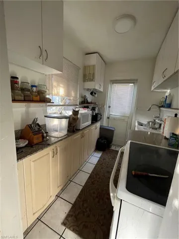 Unit 2: Kitchen with stove, light tile patterned floors, and sink