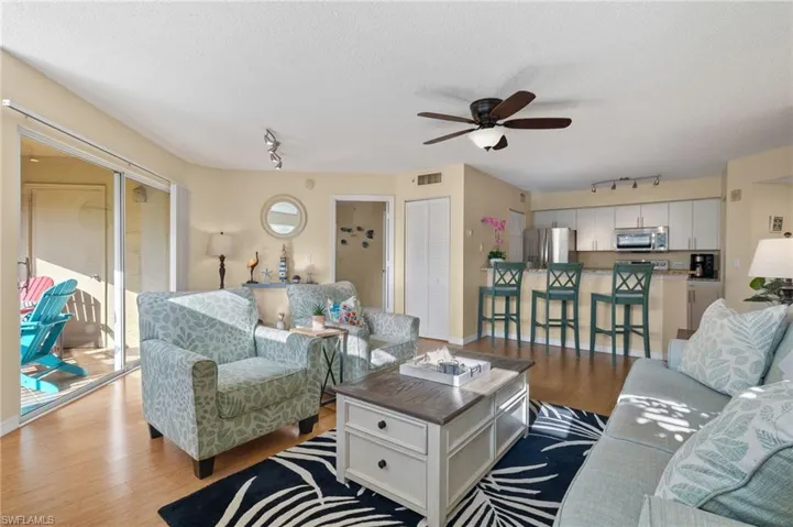 Living room featuring rail lighting, light wood-type flooring, ceiling fan, and a textured ceiling