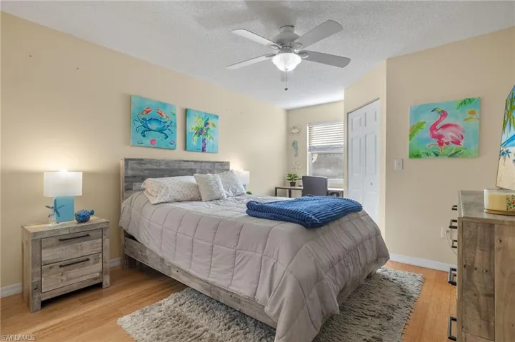 Bedroom with light hardwood / wood-style floors, a textured ceiling, a closet, and ceiling fan