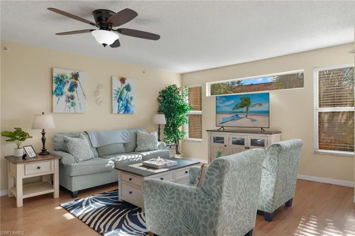 Living room featuring a textured ceiling, ceiling fan, and light hardwood / wood-style floors