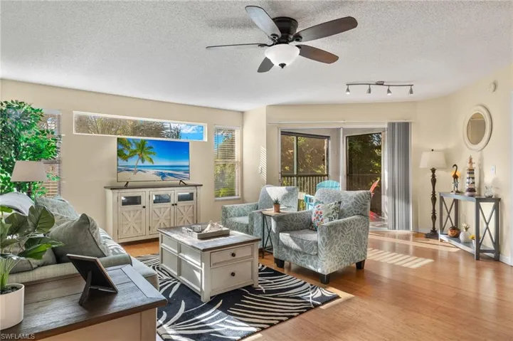 Living room with ceiling fan, rail lighting, a textured ceiling, and light hardwood / wood-style flooring