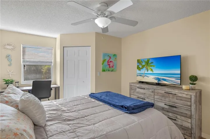 Bedroom with ceiling fan, a closet, and a textured ceiling