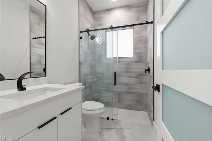 Full bath with vanity, a stall shower, and marble look tile flooring