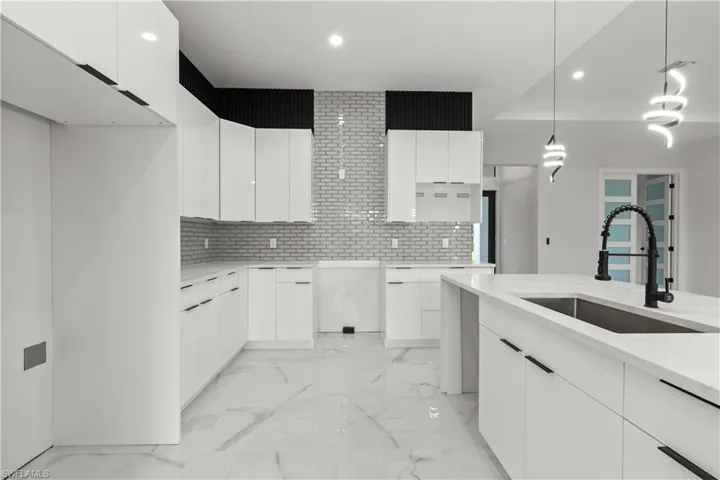 Kitchen featuring modern cabinets, recessed lighting, backsplash, pendant lighting, and white cabinetry
