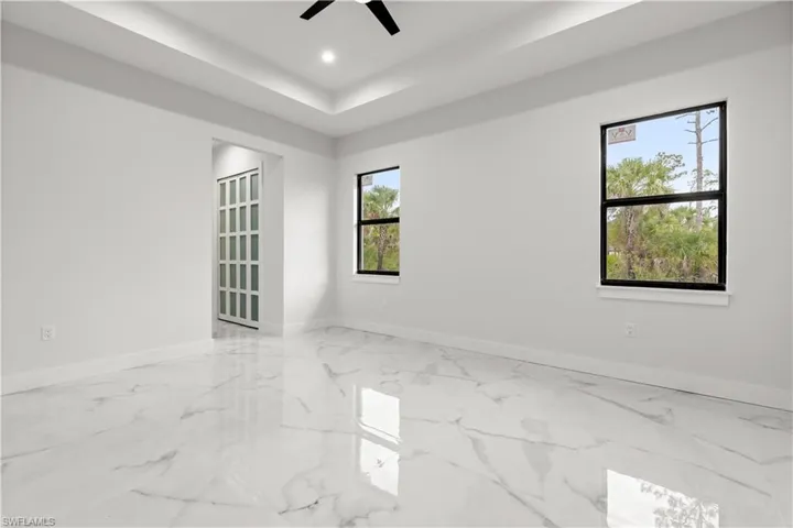Spare room with ceiling fan, marble finish floors, recessed lighting, and a tray ceiling