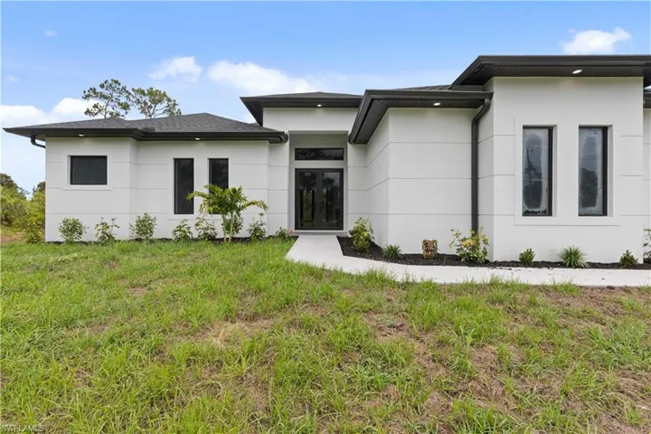 View of front of home featuring stucco siding and a front lawn
