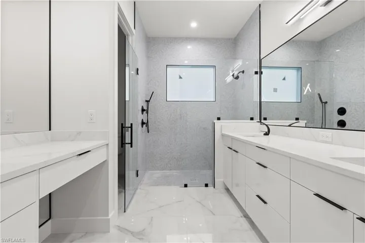 Full bathroom with double vanity, a marble finish shower, marble finish floors, and recessed lighting