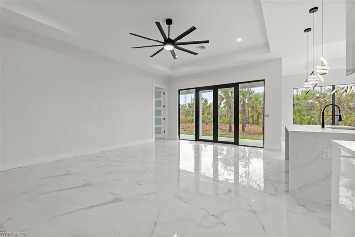 Spare room with a tray ceiling, ceiling fan, light marble finish floors, and recessed lighting