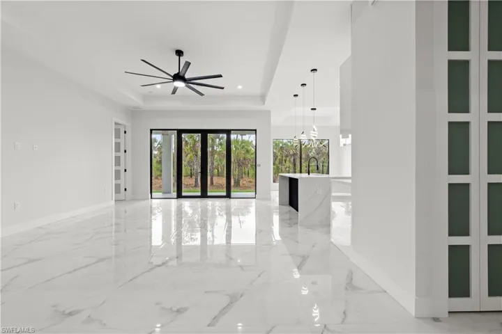 Empty room with a tray ceiling, light marble finish floors, ceiling fan, and recessed lighting