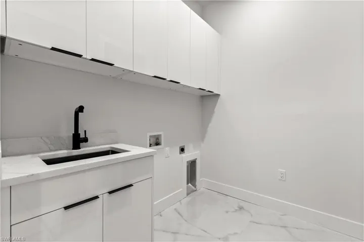 Laundry room featuring cabinet space, electric dryer hookup, light marble finish floors, and hookup for a washing machine