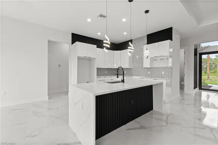 Kitchen featuring modern cabinets, white cabinetry, light marble finish flooring, and recessed lighting