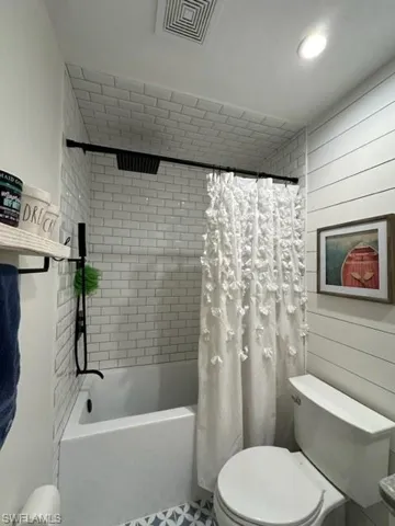 Bathroom featuring shower / bath combo with shower curtain, tile patterned floors, and toilet